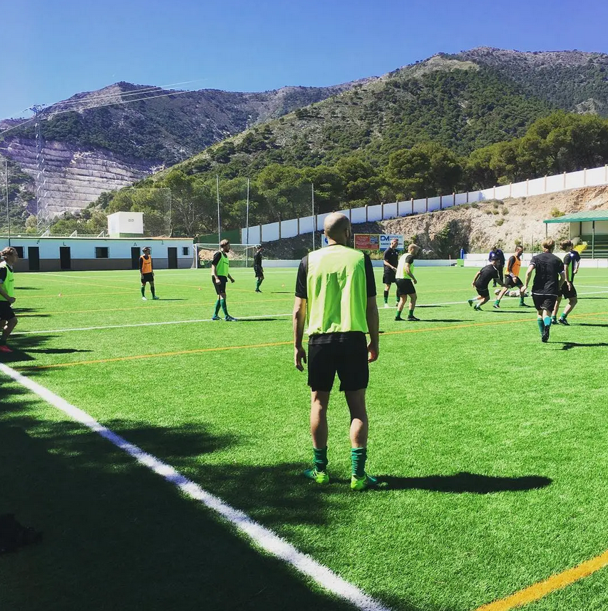 Young player running on a training pitch with mountains in the background